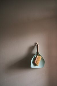 A simple dustpan and brush set hanging against a clean grey wall, perfect for cleaning concepts.