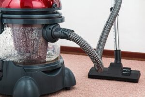 Close-up of a modern vacuum cleaner with water filtration on carpet floor indoors.